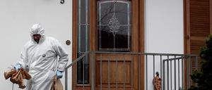 Ein Mitarbeiter der Spurensicherung trägt Papiertüten aus dem Wohnhaus des 49-jährigen Polizisten.