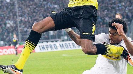 Luftnummer. Dortmunds Brasilianer Santana wird von Gladbachs Brasilianer Dante am großen Sprung gehindert. Foto: dapd