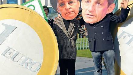 Freund oder Feind? Einen „Grundsatzkonflikt“ dementieren Kanzlerin Merkel und Frankreichs Präsident Sarkozy, die hier von Demonstranten in Berlin veralbert werden.