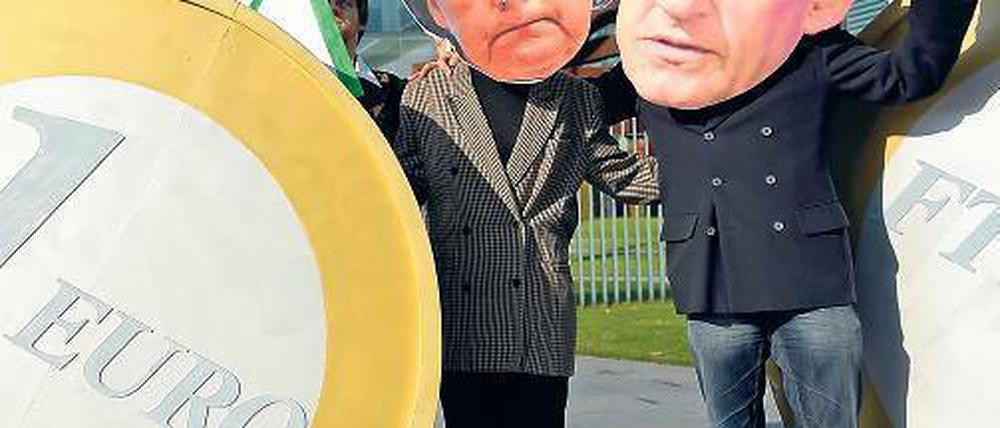 Freund oder Feind? Einen „Grundsatzkonflikt“ dementieren Kanzlerin Merkel und Frankreichs Präsident Sarkozy, die hier von Demonstranten in Berlin veralbert werden.