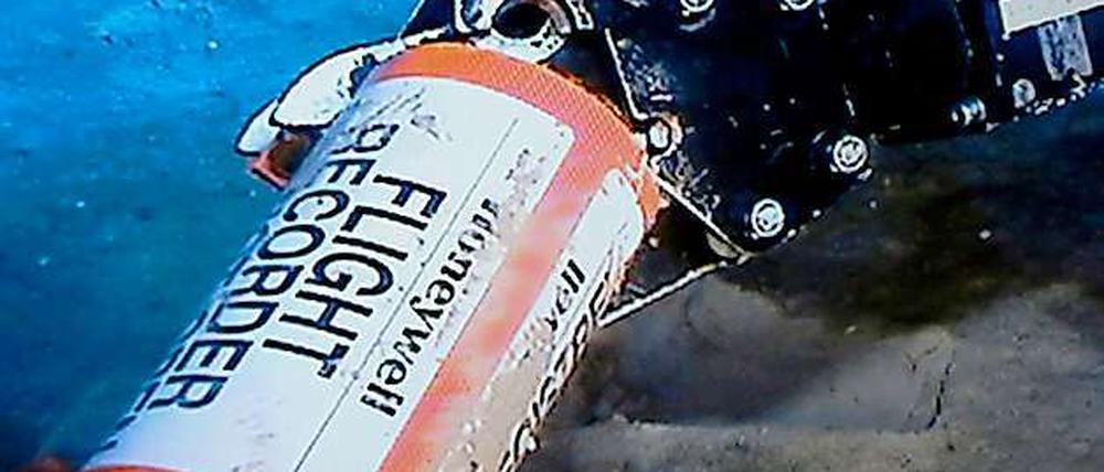 Der mechanische Arm eines Roboters greift nach dem Flugrekorder am Boden des Ozeans.