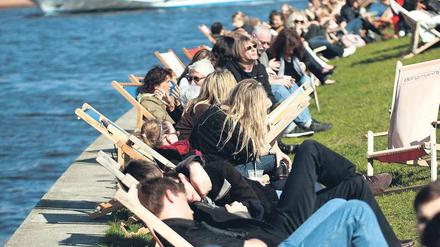 Alle am Fluss. Die Bar Capital Beach an der Spree hat bereits geöffnet, bei Sonnenschein machen es sich dort hunderte Menschen in den Liegestühlen bequem.