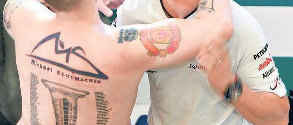 Schumi auf der Haut. Michael Schumacher wird in Malaysia von einem Fan umarmt, der seiner Liebe zu seinem Idol mit Tattoos Ausdruck verleiht. Foto: Reuters