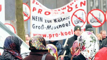 Gegen Moscheen marschieren Gruppen wie Pro Köln – hier beim Richtfest der Kölner Ditib-Moschee im Februar, beobachtet von türkischen Frauen. Was als fremd gilt und ausgegrenzt wird, kann sich jedoch ändern. Foto: Knippertz/dapd