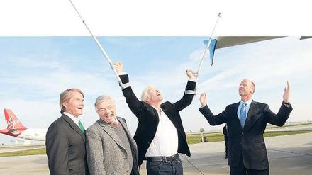 Preiset die Herren. Virgin-Gründer Richard Branson hebt die Krücken, Airbus-Chef Thomas Enders die Arme, und auch zwei Untergebene machen auf Show.