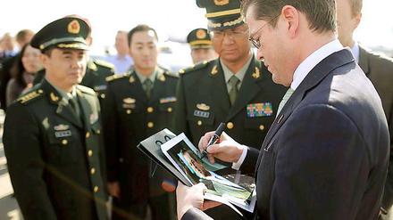 Autogramm. Guttenberg signiert vor seiner Abreise aus Peking Porträtfotos. 