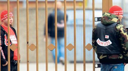 Alles unter Kontrolle. Hells-Angels-Mitglieder kontrollieren am Sonnabend die vergitterte Einfahrt zu ihrem Clubgelände in Hohenschönhausen. In den Straßen drumherum wachte ein großes Polizeiaufgebot. Foto: Davids