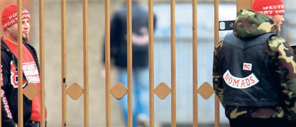 Alles unter Kontrolle. Hells-Angels-Mitglieder kontrollieren am Sonnabend die vergitterte Einfahrt zu ihrem Clubgelände in Hohenschönhausen. In den Straßen drumherum wachte ein großes Polizeiaufgebot. Foto: Davids