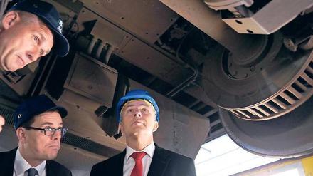 An der Achse des Bösen. S-Bahn-Chef Peter Buchner (Mitte) und ein Mitarbeiter erklären Klaus Wowereit im Werk Grünau die gängigen Schadensprüfverfahren. Foto: Jens Kalaene/dpa