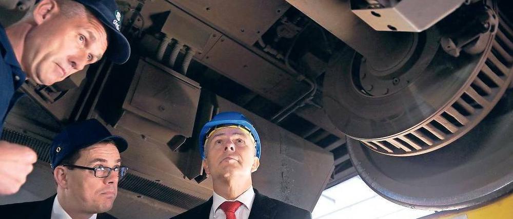 An der Achse des Bösen. S-Bahn-Chef Peter Buchner (Mitte) und ein Mitarbeiter erklären Klaus Wowereit im Werk Grünau die gängigen Schadensprüfverfahren. Foto: Jens Kalaene/dpa