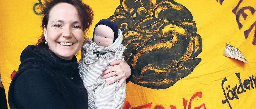 Hebamme mit Gehilfin. Die Puppe Emma nimmt Christiane Klimisch oft mit zu Patientinnen. Im Hintergrund ist ihr Banner für die Demonstration zu sehen.