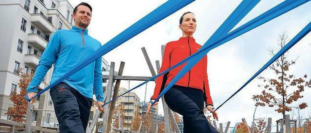 Ziehen und strecken. Die Personal Trainer Andrea Göhre und Sven Röhr zeigen, wie man das Theraband nach hinten dehnt und dabei ein Bein nach vorn führt. Eine Übung fürs Gleichgewicht. 