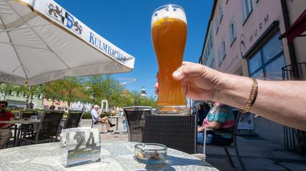 Ein Mann hält ein Glas mit Weißbier im Außenbereich von einer Eisdiele in Tirschenreuth hoch.