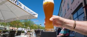 Ein Mann hält ein Glas mit Weißbier im Außenbereich von einer Eisdiele in Tirschenreuth hoch.