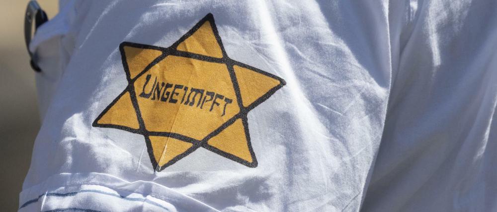 "Ungeimpft" steht auf einem nachgebildeten Judenstern am Arm eines Mannes.