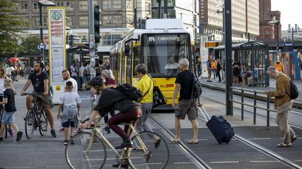 Passanten an einer BVG-Tramhaltestelle am Alexanderplatz.