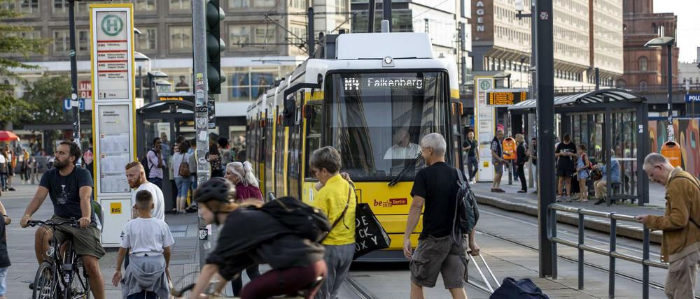 Passanten an einer BVG-Tramhaltestelle am Alexanderplatz.