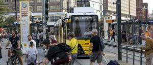 Passanten an einer BVG-Tramhaltestelle am Alexanderplatz.