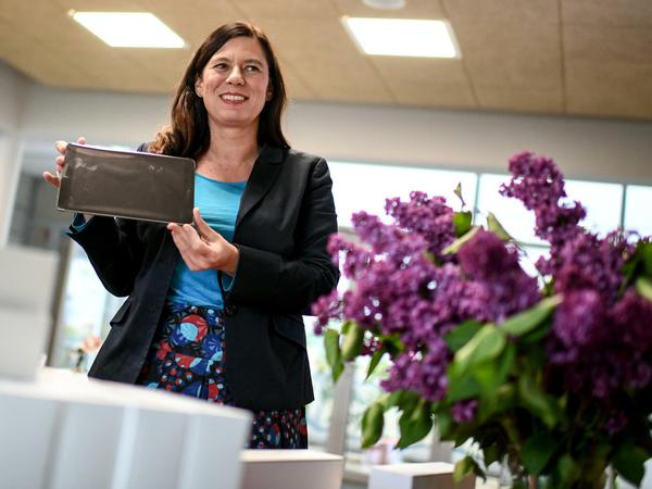 Sandra Scheeres hält ein in Folie verpacktes Tablet in den Händen und lächelt.