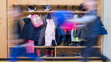 Zwei Kinder rennen an einer Garderobe in einer Kita vorbei.