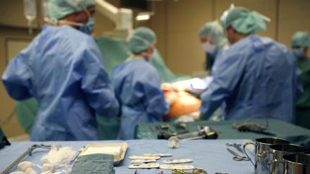 Chirurgen operieren in einer Klinik einen Patienten, im Vordergrund liegt Operationsbesteck.