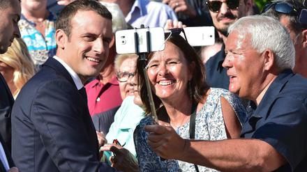 Frankreichs Präsident Emmanuel Macron lässt sich bei einem Wahllokal mit Anhängern für ein Selfie fotografieren, bevor er seine Stimme für die Parlamentswahl abgibt. 