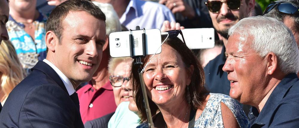Frankreichs Präsident Emmanuel Macron lässt sich bei einem Wahllokal mit Anhängern für ein Selfie fotografieren, bevor er seine Stimme für die Parlamentswahl abgibt. 