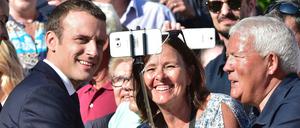 Frankreichs Präsident Emmanuel Macron lässt sich bei einem Wahllokal mit Anhängern für ein Selfie fotografieren, bevor er seine Stimme für die Parlamentswahl abgibt. 