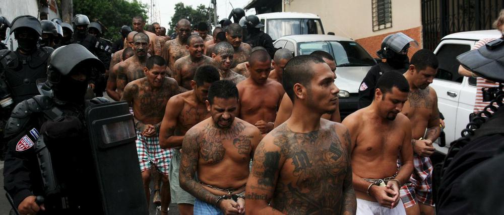 Mitglieder der Gang Mara Salvatrucha in El Salvador werden von Polizisten ins Gefängnis begleitet. 