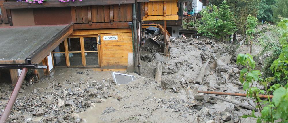 Von Schlamm und Gestein sind Häuser in Oberstdorf (Bayern) am Sonntag umgeben nachdem andauernder Regen eine Schlammlawine ausgelöst hatte. Ein bedrohtes Wohngebeit mit bis zu 500 Menschen wurde vorsorglich evakuiert.