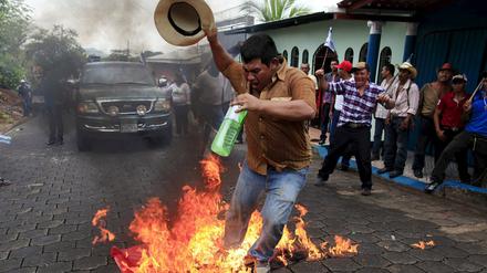 Ein Demonstrant in Nicaragua verbrennt bei den Protesten gegen den Bau des Nicaragua-Kanals eine Flagge der Sandinisten am Samstag in Juigalpa City. Die chinesische Betreibergesellschaft HKND will die 278 Kilometer lange Verbindung zwischen dem Pazifischen Ozean und der Karibik bis 2019 fertigstellen.