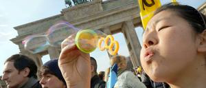 Menschen bei der Demonstration "Vergesst Fukushima nicht!" vor dem Brandenburger Tor. Eine Teilnehmerin bläst Seifenblasen.