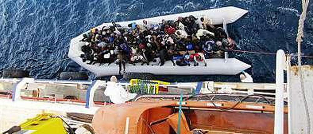 Ein Flüchtlingsboot neben dem Frachtschiff "OOC Cougar". Die Schiffe der Reederei Opielok Offshore Carriers haben seit Dezember vergangenen Jahres mehr als 1500 Menschen aus dem Mittelmeer gerettet. 