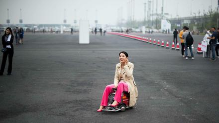 Made in China. Eine Chinesin demonstriert vor dem Messegelände ein selbst konstruiertes Minimobil.