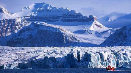 Forscher fahren im Polarmeer mit einem Boot durch die bizarre Landschaft bei Ny-Ålesund auf Spitzbergen (Norwegen). Im Hintergrund die Kongsfjord-Gletscherfront.