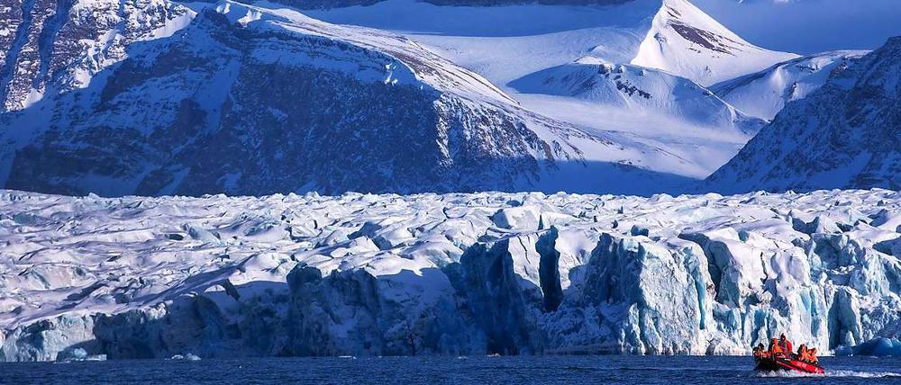 Forscher fahren im Polarmeer mit einem Boot durch die bizarre Landschaft bei Ny-Ålesund auf Spitzbergen (Norwegen). Im Hintergrund die Kongsfjord-Gletscherfront.