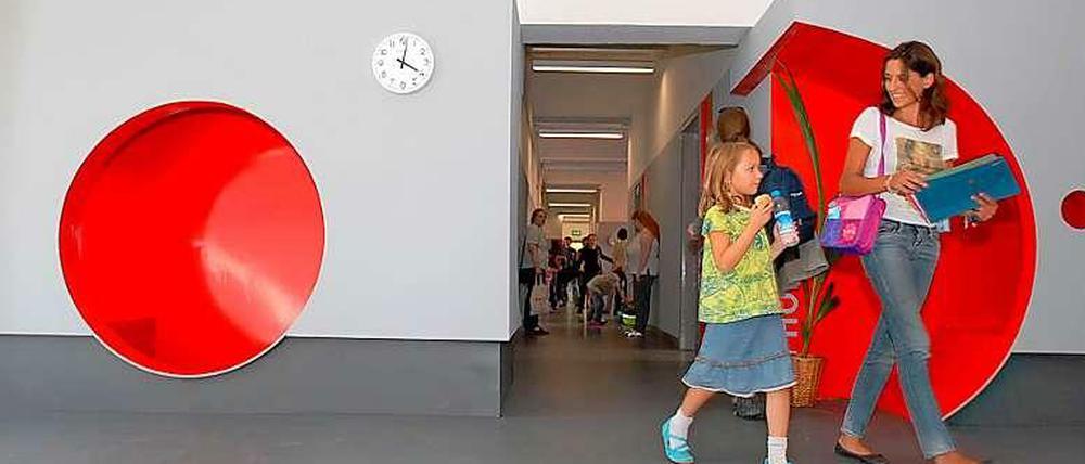 Eine Mutter geht mit ihrer Tochter durch den Korridor einer Schule.