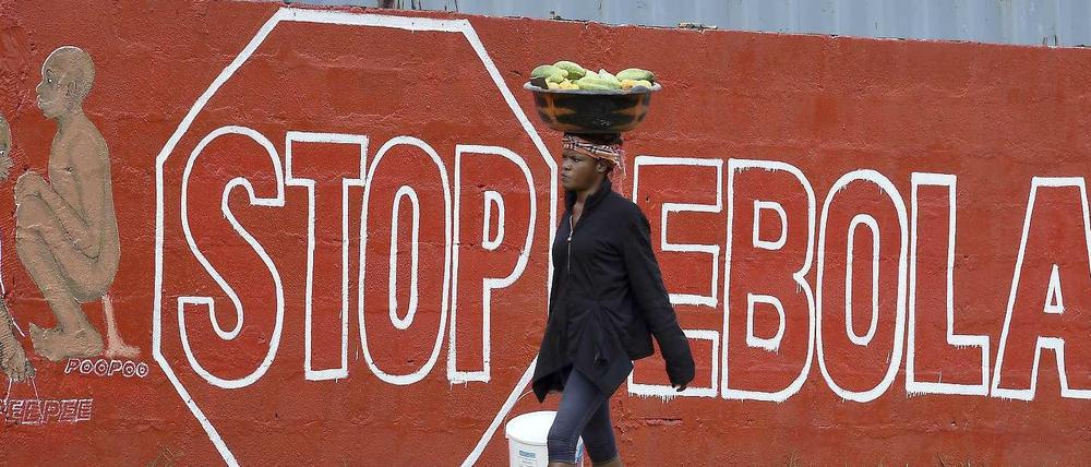 Eine Frau in Sierra Leone geht an einer Wand mit der Aufschrift "Stop Ebola" vorbei. In dem westafrikanischen Land wurde eine erneute Ausgangssperre angekündigt.