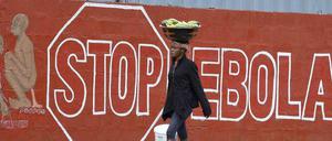 Eine Frau in Sierra Leone geht an einer Wand mit der Aufschrift "Stop Ebola" vorbei. In dem westafrikanischen Land wurde eine erneute Ausgangssperre angekündigt. 
