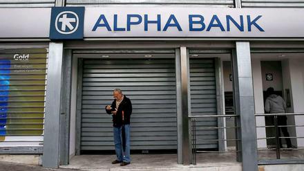 Ein Mann hebt an einem Geldautomaten in Athen Geld ab. Die Banken blieben in Griechenland am Montag wegen eines Feiertages geschlossen.