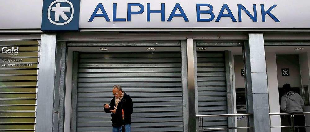 Ein Mann hebt an einem Geldautomaten in Athen Geld ab. Die Banken blieben in Griechenland am Montag wegen eines Feiertages geschlossen.