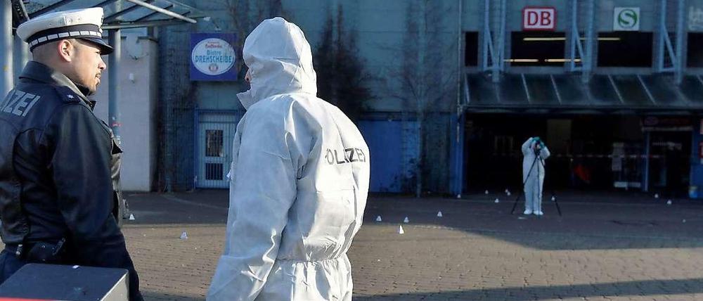 Ein Polizist und Mitarbeiter der Spurensicherung stehen am Mittwoch in Stuttgart hinter einem Polizeiabsperrband. Zuvor hatte es in den frühen Morgenstunden einen Schusswechsel zwischen der Polizei und einem Mann gegeben.