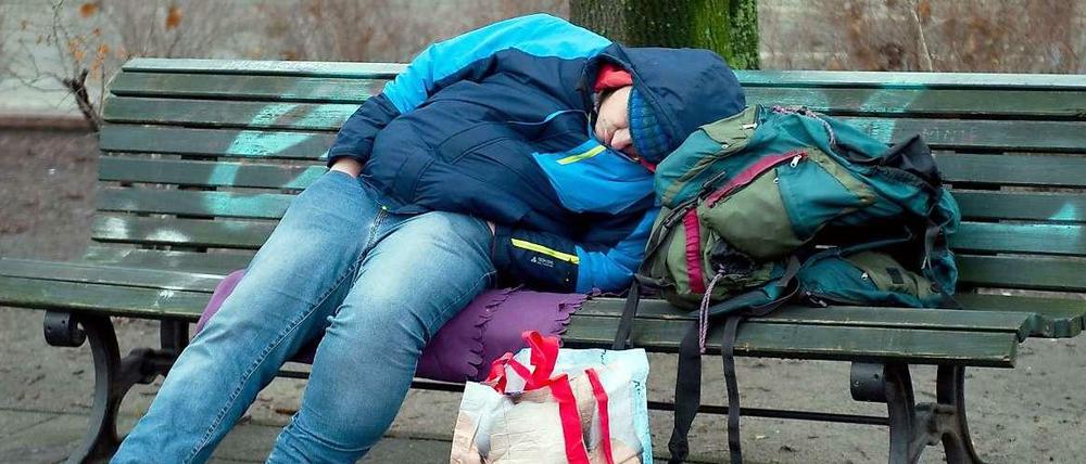 Ein Obdachloser schläft in einem Berliner Park auf einer Bank. Die Berliner Armut verbirgt sich aber meistens, denn am stärksten von Armut bedroht sind Alleinerziehende und Kinder.