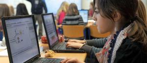 Jugendliche arbeiten in einem Klassenzimmer an Laptops.