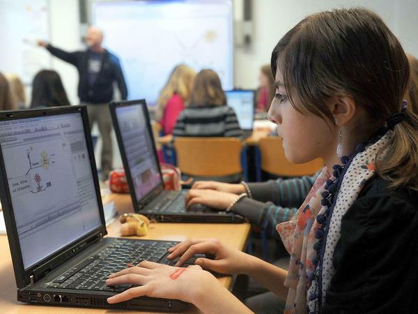 Jugendliche arbeiten in einem Klassenzimmer an Laptops.