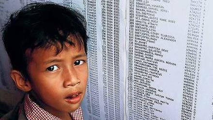 Ein Junge schaut auf die am Flughafen in Surabaya ausgehängte Passagierliste. 