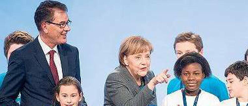 Blauer Planet, blaue Mappe. Entwicklungsminister Gerd Müller überreicht Kanzlerin Angela Merkel die „Charta“.