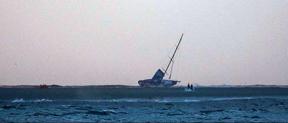 Landgang. Die Rennyacht Vestas Wind liegt auf die Seite geworfen auf einer Sandbank im Indischen Ozean. 