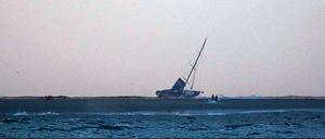 Landgang. Die Rennyacht Vestas Wind liegt auf die Seite geworfen auf einer Sandbank im Indischen Ozean. 