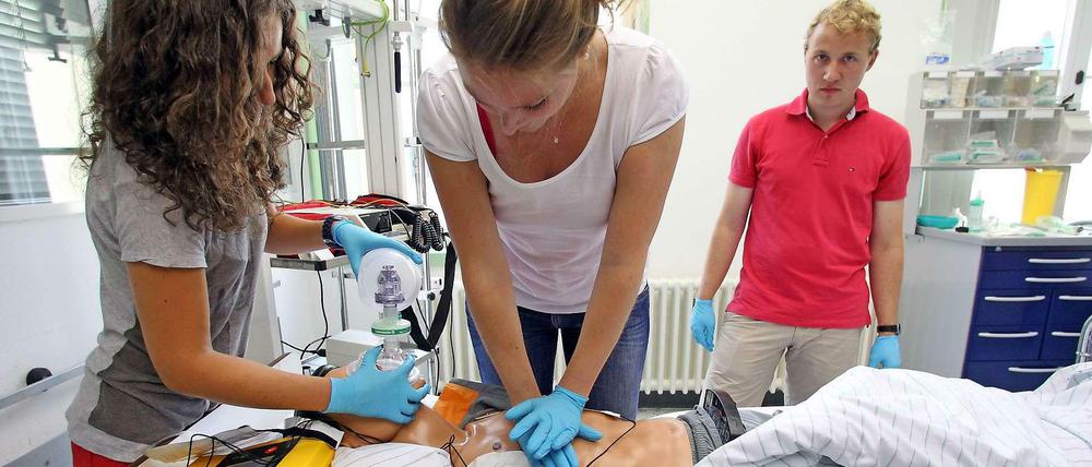 Medizinstudierende üben an einer Puppe.